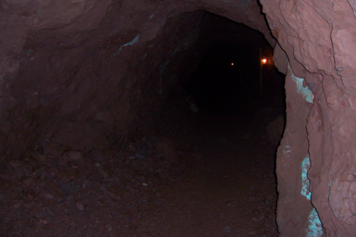 Interior: Mine shaft. Cavernous rock stretches into darkness. Two lights glow weakly in the black.